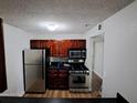 Kitchen with stainless steel appliances, wooden cabinets, and dark countertops at 2031 Dixie Belle Dr # Q, Orlando, FL 32812
