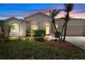Inviting single-story home with manicured lawn, tasteful landscaping, fountain, and warm exterior lighting at dusk at 213 Strathmore Cir, Kissimmee, FL 34744