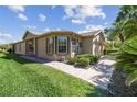 Attractive single-story home featuring a well-manicured lawn, lush landscaping, and charming brick paver walkway at 238 Acadia Dr, Poinciana, FL 34759