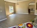 Open living room with wood-look flooring, neutral walls, and an arched doorway to an adjacent space at 2520 Azzurra Ln, Ocoee, FL 34761