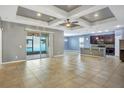 Open-concept living room and kitchen area with tile floors and a tray ceiling with fan at 3131 Bass Boat Way, Kissimmee, FL 34746