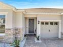 Close-up of front entrance with stone accents, manicured landscaping, and a convenient three-car garage at 4717 Weatherbell Rd, Winter Garden, FL 34787