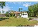 Lawn view of this home with a two-car garage, pretty landscaping, and lots of curb appeal at 6495 Fall St, St Cloud, FL 34771