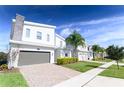 View of a street with modern two-story homes, brick-paved driveways, and well-maintained lawns at 8817 Cruden Bay Ct, Davenport, FL 33896