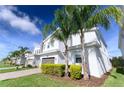 Contemporary two-story home with white exterior, gray accents, and lush palm trees at 8817 Cruden Bay Ct, Davenport, FL 33896