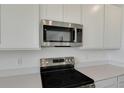 Close-up of stainless steel microwave and electric range cooktop, complemented by quartz countertops and white cabinets at 1107 Olivine Ave, Dundee, FL 33838