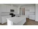 Bright kitchen with stainless steel appliances, quartz countertops, island, and wood-look flooring at 1107 Olivine Ave, Dundee, FL 33838