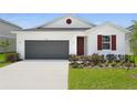Front elevation featuring a white exterior, gray garage door, and fresh landscaping at 1134 Olivine Ave, Dundee, FL 33838