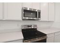 Close-up of modern stainless steel microwave and range top, accented by white cabinetry at 1134 Olivine Ave, Dundee, FL 33838
