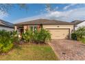 Beautiful single-story home featuring lush landscaping and a brick-paved driveway leading to a two-car garage at 1187 Playa Del Sol Ln, St Cloud, FL 34771