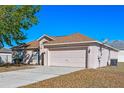 Single-story home with neutral siding, front-facing two-car garage, driveway, and well-maintained lawn at 258 Grouper Ct, Kissimmee, FL 34759