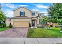 Two-story home featuring a well-maintained lawn, brick driveway, and an attached two-car garage at 624 Sardinia Circle, Davenport, FL 33837