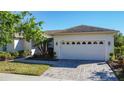 This home features a large two-car garage with an attractive brick-paved driveway and lush landscaping at 657 Shorehaven Dr, Poinciana, FL 34759