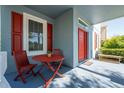 Inviting front porch featuring a cozy seating area with red chairs and table at 6919 Cupseed Ln, Harmony, FL 34773