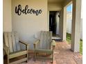 Charming front porch with brick floor, two chairs and welcome sign, inviting entrance to the home at 813 Marcel Loop, Davenport, FL 33837