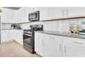 Modern kitchen with white cabinetry, gray countertops, stainless steel appliances, and subway tile backsplash at 1023 Wisteria Way, Dundee, FL 33838
