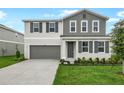 Charming two-story home featuring gray and white colors, a landscaped yard, and a two car garage at 1031 Wisteria Way, Dundee, FL 33838