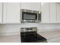 Modern kitchen boasting stainless steel microwave and stovetop, complemented by sleek white cabinets at 1031 Wisteria Way, Dundee, FL 33838