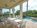 View of an outdoor dining table under a covered patio, showcasing the pool and surrounding greenery at 1057 Castle Pines Ct, Reunion, FL 34747