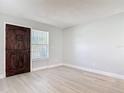 Bright living room with new gray vinyl floors, fresh paint, and a stylish dark wood door, ready for personal touches at 1085 Whitewood Dr, Deltona, FL 32725