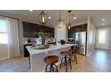 Open kitchen with a white island, pendant lighting, stainless steel appliances, and dark cabinets at 1110 Olivine Ave, Dundee, FL 33838