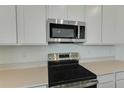 Close up on stainless steel appliances, white cabinets, and quartz countertops in a well lit, modern kitchen at 1118 Olivine Ave, Dundee, FL 33838