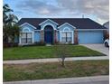 Inviting one-story home with lush green lawn, blue exterior, and attached garage at 12966 Broakfield Cir, Orlando, FL 32837