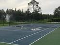Outdoor community tennis court with a lush green background featuring a fountain at 14049 Fairway Island Dr # 127, Orlando, FL 32837