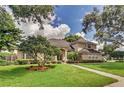 Beautifully landscaped front yard leading to a tan home with a gray roof and arched entryway at 3637 Rothbury Dr, Belle Isle, FL 32812