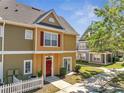 Lovely townhouse with red door, sidewalk, manicured lawn, and mature tree at 4561 Yellowgold E Rd # 107, Kissimmee, FL 34746