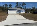 Charming single-story home featuring a blue exterior, white accents, a gray roof, and a concrete driveway at 4863 Sw 159Th Ln Rd, Ocala, FL 34473