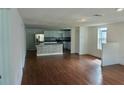 Open-concept living space with hardwood floors, white walls, and an integrated kitchen area at 516 W 7Th St, Lakeland, FL 33805