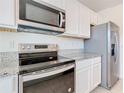 Close-up of kitchen appliances, stainless steel range and microwave with white cabinetry at 12035 Holystone St, Winter Garden, FL 34787