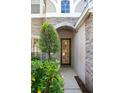 Inviting entryway featuring a decorative front door, stone accents, and lush landscaping at 1607 Tail Feather Dr, Kissimmee, FL 34746