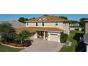 A well-maintained two-story home, showcasing a brick paver driveway, landscaping, and a three-car garage at 1915 Acacia Dr, Kissimmee, FL 34758
