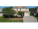 A beautiful two-story home featuring lush landscaping, a well-manicured lawn, and a brick paver driveway at 1915 Acacia Dr, Kissimmee, FL 34758