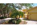 Landscaped yellow home featuring brick-paver driveway, walkway and mature trees at 2502 Palm Tree Dr, Poinciana, FL 34759