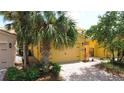Attached two-car garage and manicured landscaping on yellow home featuring brick-paver driveway at 2502 Palm Tree Dr, Poinciana, FL 34759