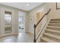 Elegant foyer featuring a decorative front door, tiled flooring, and a staircase with carpeted steps at 2967 Gavin Sky Dr, Kissimmee, FL 34744