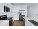 Modern white kitchen featuring an island with quartz countertops, stainless steel appliances, and wood-look tile flooring at 2967 Gavin Sky Dr, Kissimmee, FL 34744