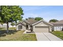 Charming single-story home with a well-manicured lawn and a two-car garage during daylight at 323 Azincourt Ln, Kissimmee, FL 34759