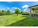 Expansive backyard featuring lush green grass, mature trees and a covered patio with decorative outdoor furniture at 3447 Feathergrass Ct, Harmony, FL 34773