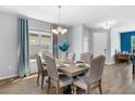 Formal dining room with hardwood floors, a modern chandelier and lots of natural light from the large window at 3447 Feathergrass Ct, Harmony, FL 34773