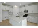 Bright, all-white kitchen featuring an island with sink and stainless steel appliances at 4075 Bannock Ave, Tavares, FL 32778
