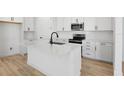 Modern kitchen featuring white cabinets, an island, and stainless steel appliances at 4076 Bannock Ave, Tavares, FL 32778