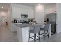 Bright kitchen featuring stainless steel appliances, white cabinets, and a large center island with barstool seating at 5140 Four Strand Ct, St Cloud, FL 34772