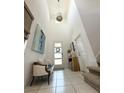 The foyer features a high ceiling, tile floor, and a bench with decorative pillows at 6608 Harper Way, Harmony, FL 34773