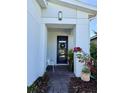 The front door of a white house features a decorative wreath, plants, and a white bench at 6608 Harper Way, Harmony, FL 34773