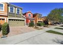 Exterior view of colorful townhomes featuring brick driveways and lush landscaping at 9535 Silver Buttonwood St, Orlando, FL 32832