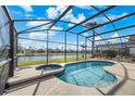 Relaxing screened-in pool and spa overlooking a picturesque waterfront view with comfortable lounge seating at 1048 Lake Berkley Dr, Kissimmee, FL 34746